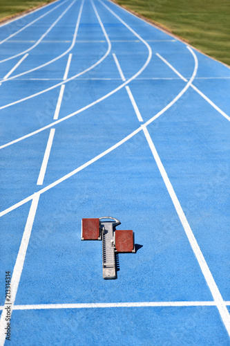 Starting blocks on blue running tracks lanes at track and field. Sport accessory. Vertical crop of stadium floor with copy space background. photo