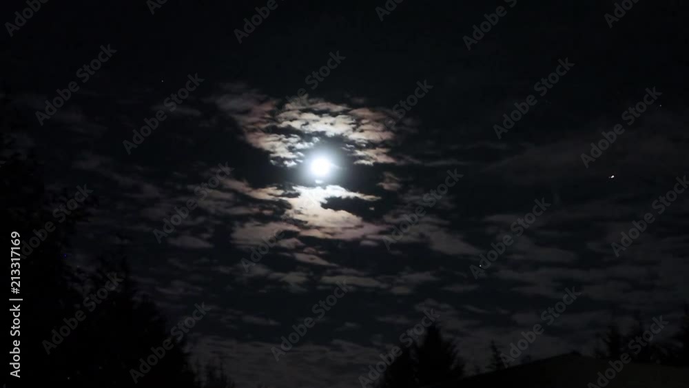 Plane flying across a moon lit night with cool clouds Plane flying across a moon lit night with cool clouds