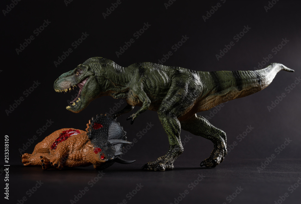 Fototapeta premium tyrannosaurus with a triceratops body nearby on dark background