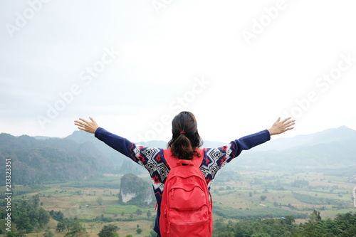Young Woman with arms in the air enjoying on the hilltop. Freedom of life and happy in beautiful landscape morning fog on the mountain.Success of adventure and freedom wanderlust concept.