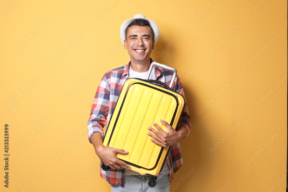 Young man with suitcase on color background Young man with suitcase on color background