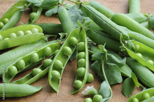 Ripe pods of green peas, fresh green peas on wooden table, close up