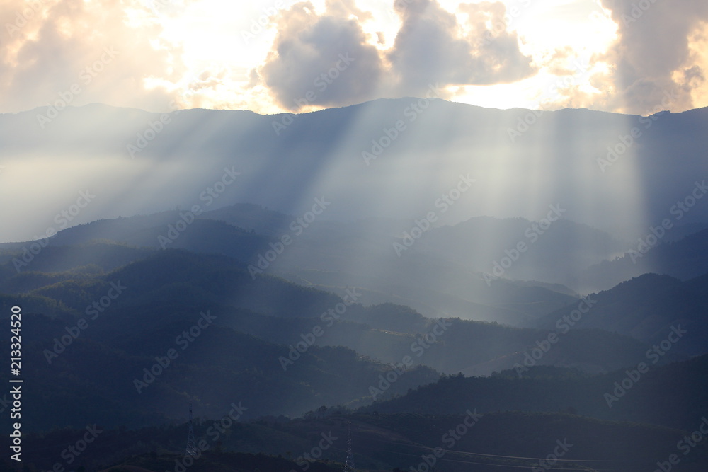 Dramatic god lights passing through clouds and shining on mountain ranges. warm light shower. God hope and dream concept Dramatic god lights passing through clouds and shining on mountain ranges. warm light shower. God hope and dream concept