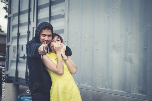 Billede på lærred The bandit locks the woman's neck by his arm for a hostage and pointing knife forward