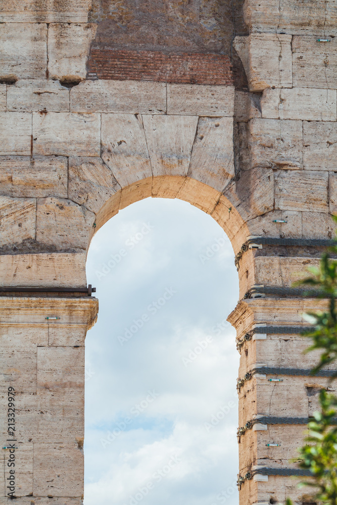 Coliseum in Rome, Italy. Architectural details on a facade. The blue sky is shown through an arch.