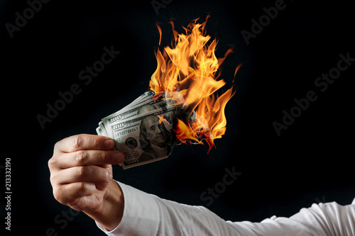 Konstfotografi Male hand close-up, holds burning money in hands, burning US dollars