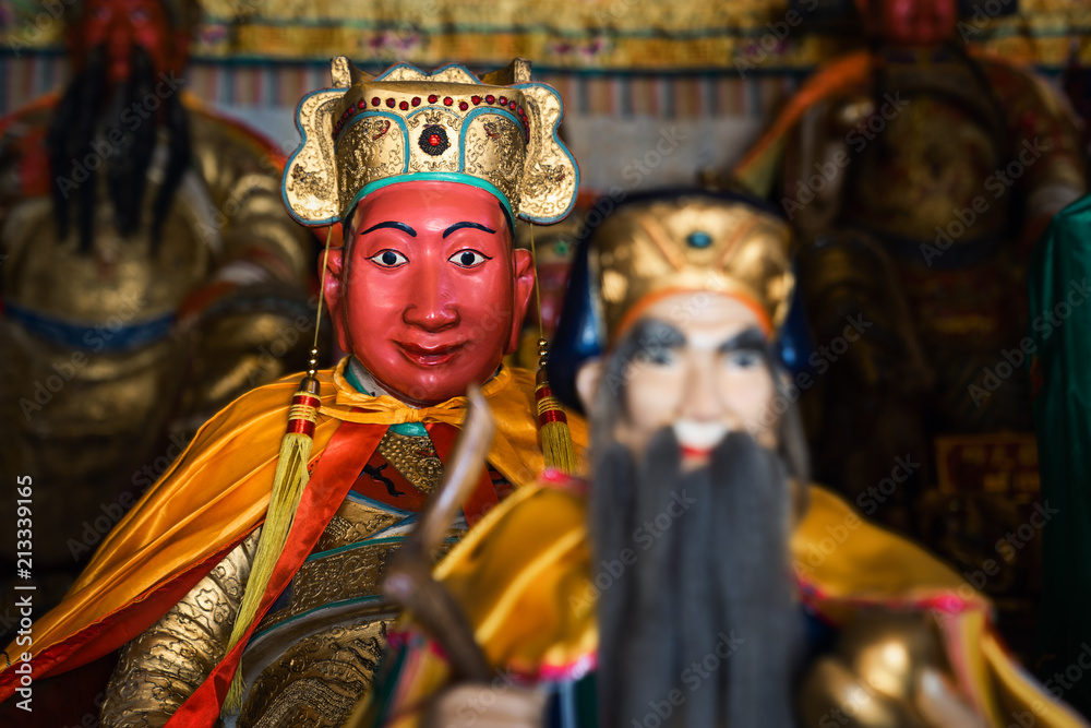Red and golden colored statue of monk in holy buddhist temple in thailand with bokeh Red and golden colored statue of monk in holy buddhist temple in thailand with bokeh