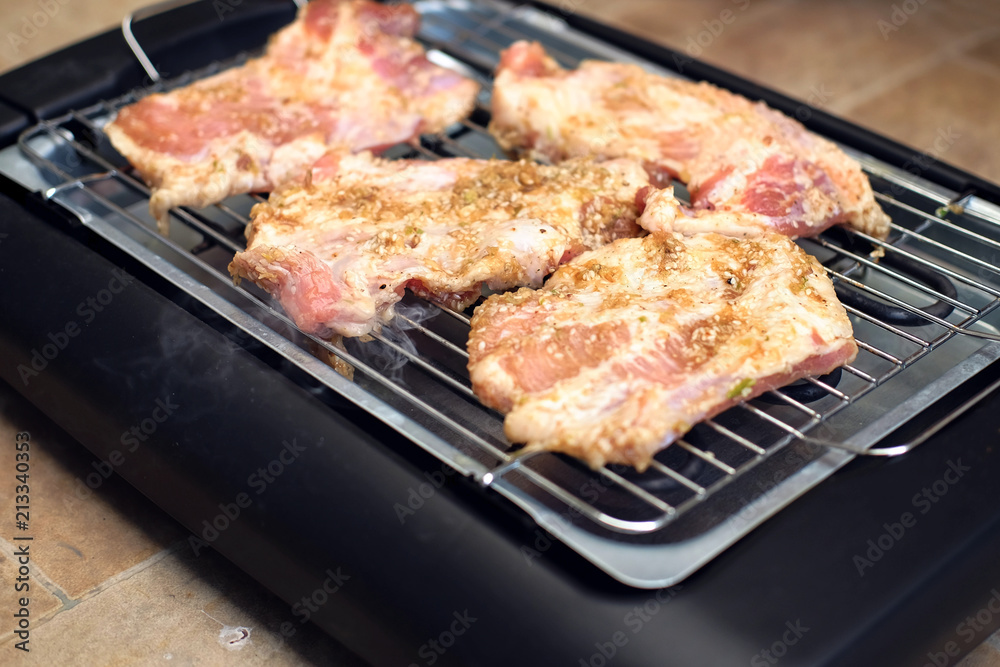 Delicious pieces of meat with spices on the electric grill. Delicious pieces of meat with spices on the electric grill.