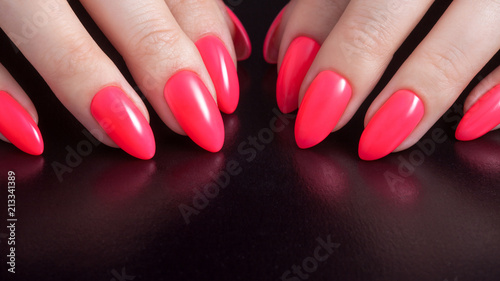 Women s hands with perfect red manicure. Nail Polish red coral color. Black background