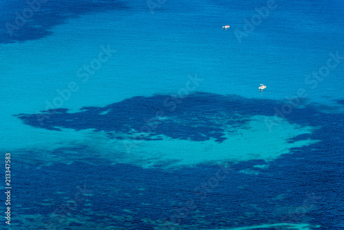 Aerial view of tropical turquoise blue sea with floating boats and people. High resolution image of sailing boats anchored next to reef around the coastline. Bird's eye view, ocean from above. © Roberto
