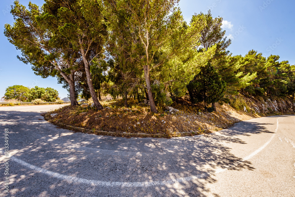 Dangerous hairpin bend on a mountain road. Hair pin corner of a narrow two way street on a hill. Blind curve covered by trees and Mediterranean vegetation. Montepellegrino, Palermo, Sicily.