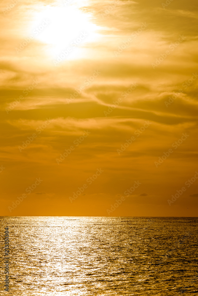 Orange sunset with golden reflection on sea. Light of setting sun shimmering on the ocean surface.