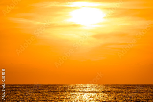 Orange sunset with golden reflection on sea. Light of setting sun shimmering on the ocean surface.