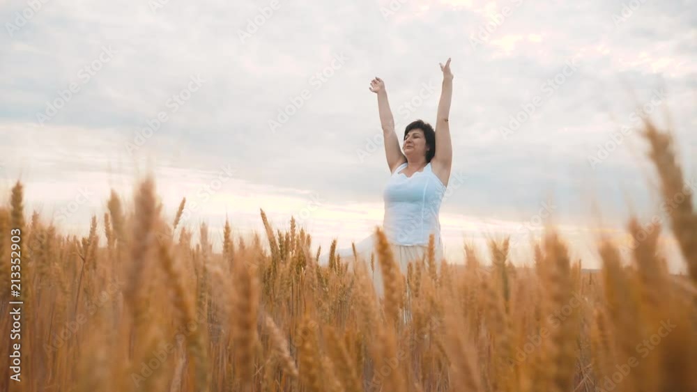 Plus size fashion model in slow motion video walking white dress on field wheat. fat woman on nature in the field grass flowers summer. agriculture lifestyle overweight female body. full girl length Plus size fashion model in slow motion video walking white dress on field wheat. fat woman on nature in the field grass flowers summer. agriculture lifestyle overweight female body. full girl length