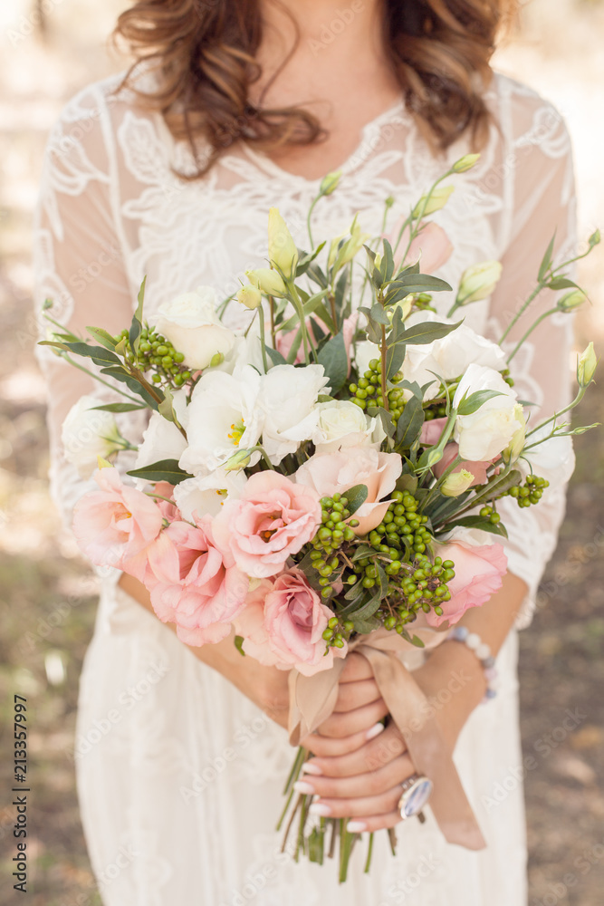 beautiful, fresh, tender bouquet of eustom, roses and greenery in the hands of a young girl on a white lace wedding dress background close-up beautiful, fresh, tender bouquet of eustom, roses and greenery in the hands of a young girl on a white lace wedding dress background close-up