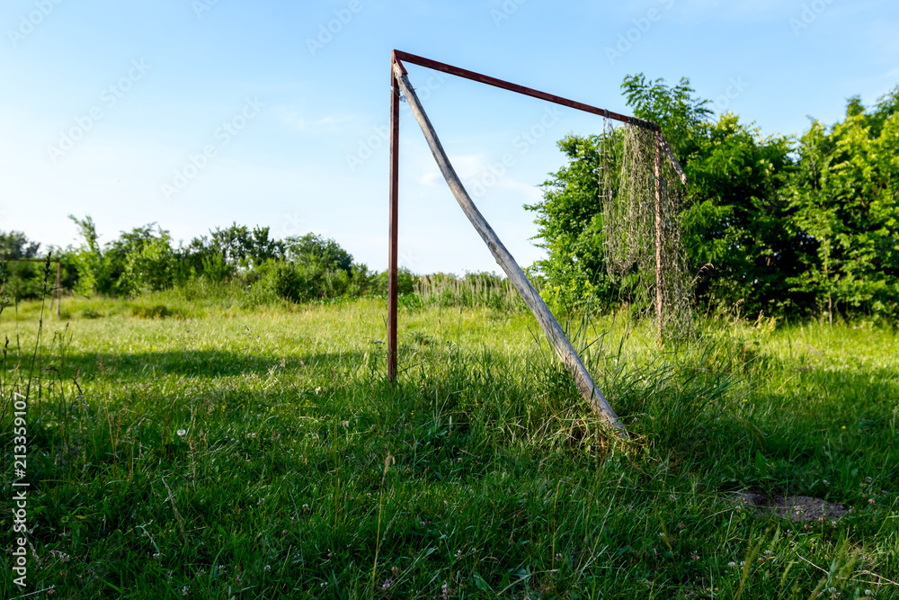 Abandoned old football court is overgrown in meadow grass