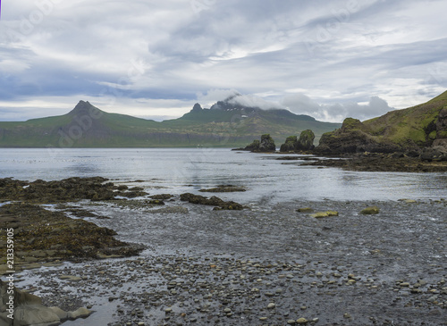 Scenic view on beautiful Hornbjarg cliffs in west fjords, remote nature reserve Hornstrandir in Iceland, rocky pebble coast with bird cliff rocks, sea and blue sky clouds background photo