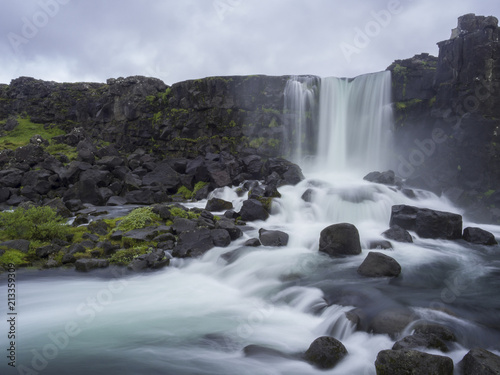 Oxararfoss waterfall in Thingvellir Iceland nature reserve with volcanic rocks and moss  falling from fissure in Mid-Atlantic Ridge  long exposure motion blur