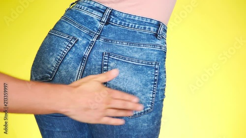 a male hand slaps the girl's buttocks. the girl in jeans seductively moves. 4k, close-up. slow-motion