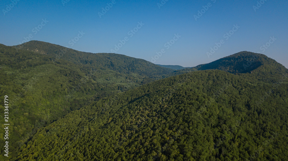 Fototapeta premium Russian Forest And Mountains Under Blue Sky By Aerial Drone. Stunning Aerial Drone Stock Footage of South russian Forest And Mountains Under Blue Sky