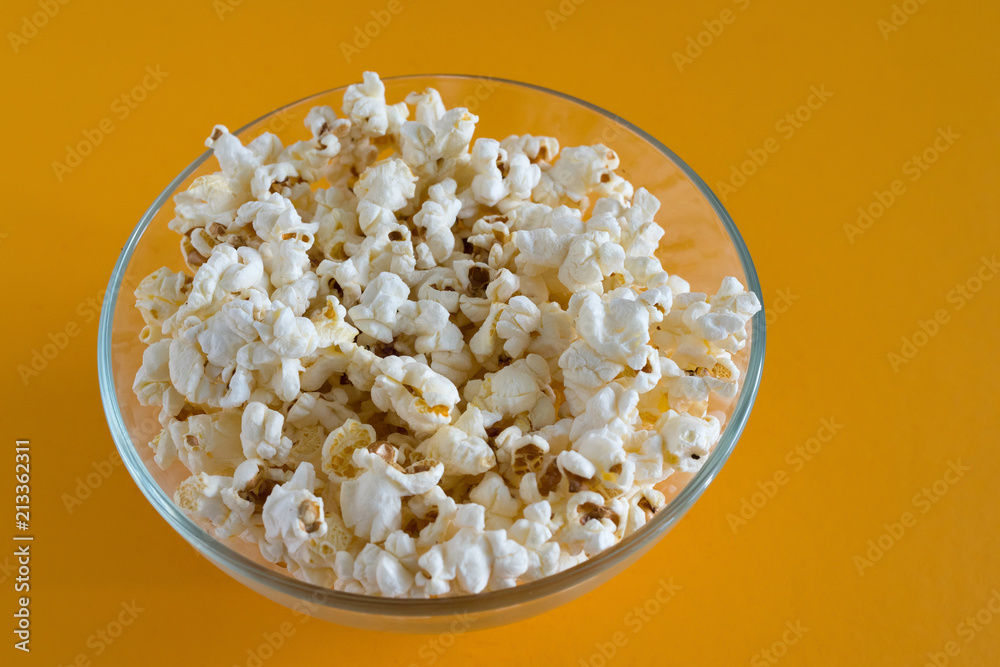 Salted popcorn grains in the box on the orange background. Salted popcorn grains in the box on the orange background.
