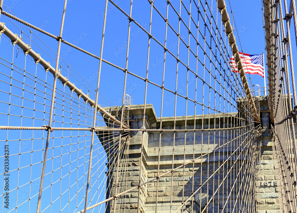 Closeup of Brooklyn Bridge and American Flag over East River, New York City, USA