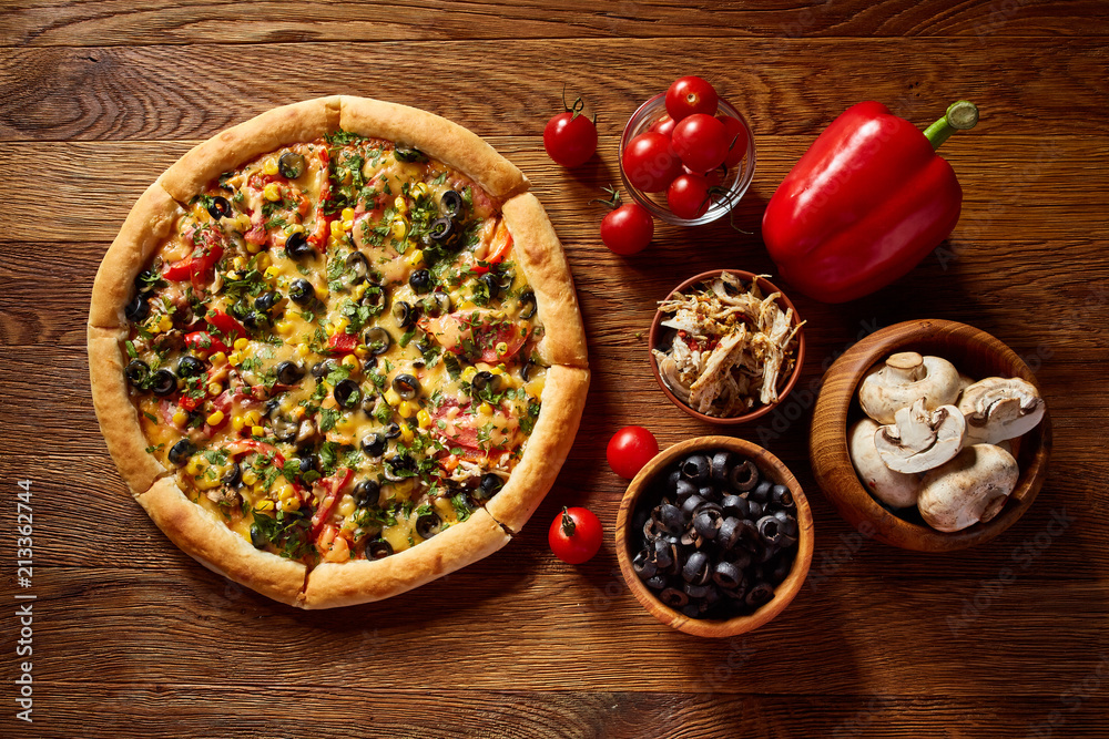 Pizza still life. Part of freshly baked pizza and its components arranged on wooden background.