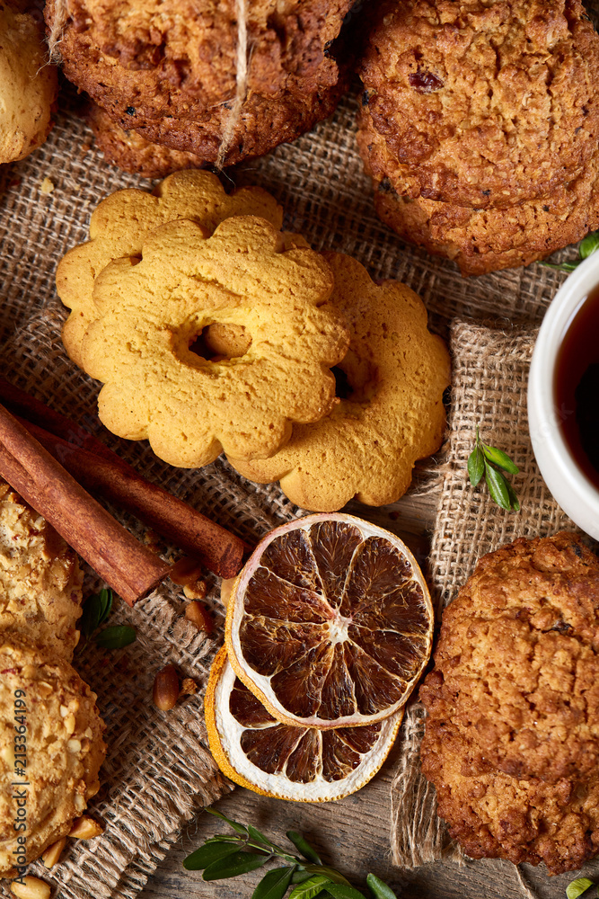 Fototapeta premium Christmas teatime with oatmeal, chocolate biscuits, and spices, on wooden background, close-up, selective focus.