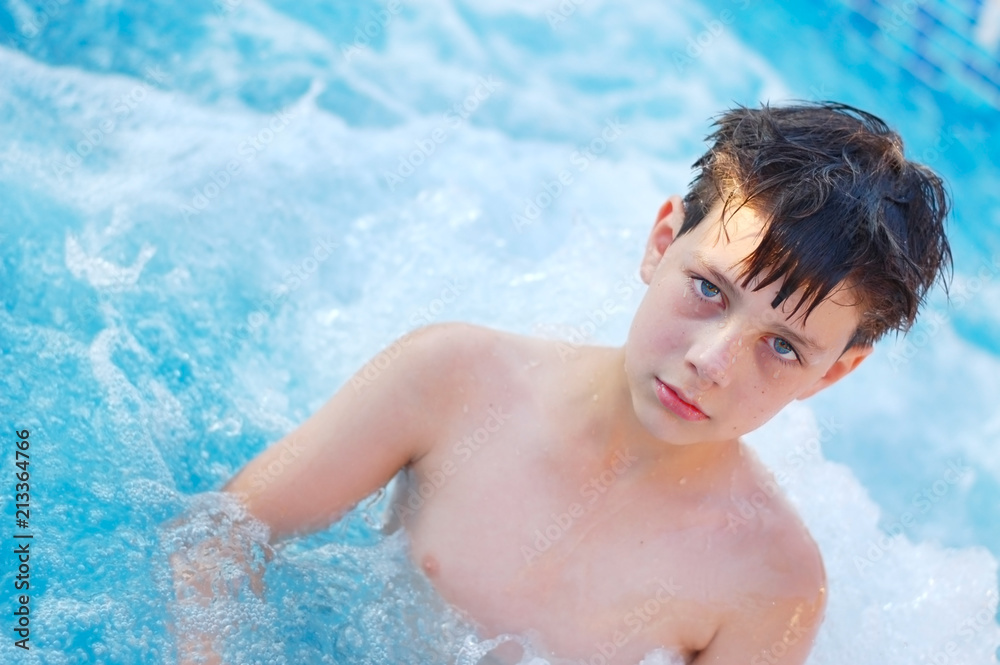 A sad boy standing in the pool in the summer in the chest in the water. He was not fun because he was already tired of swimming A sad boy standing in the pool in the summer in the chest in the water. He was not fun because he was already tired of swimming
