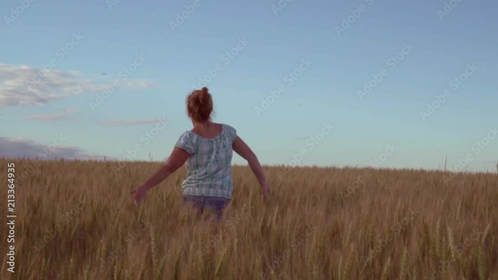 The joyful girl slightly jumping runs on the field with wheat.
The joyful girl slightly jumping runs on the field with wheat.