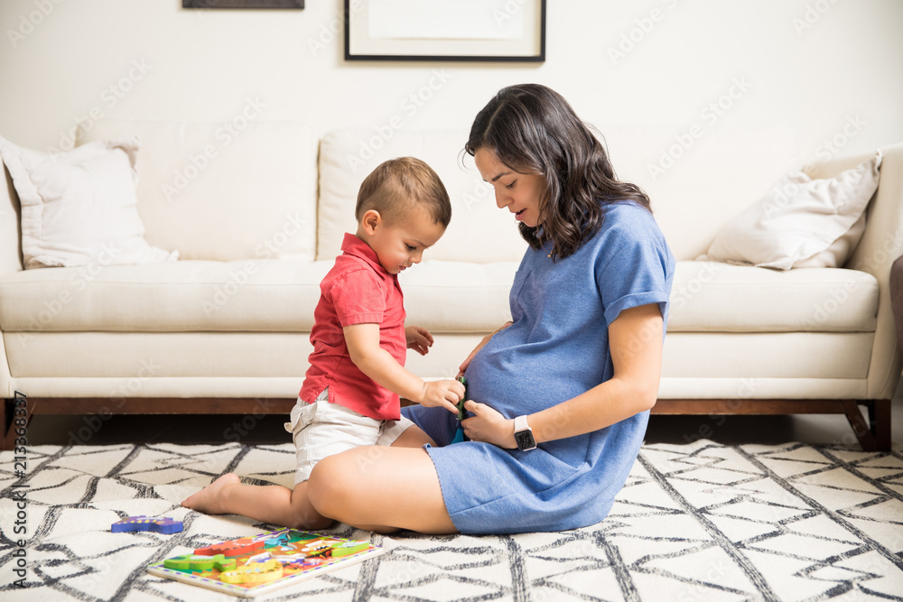 Boy Playing With Fetus In Pregnant Mother's Stomach At Home Boy Playing With Fetus In Pregnant Mother's Stomach At Home