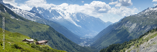 a view of the chamonix valley from the alpine mountains in the Vallorcine area with foreground of alpine meadows on a clear summer day with blue sky and bright clouds