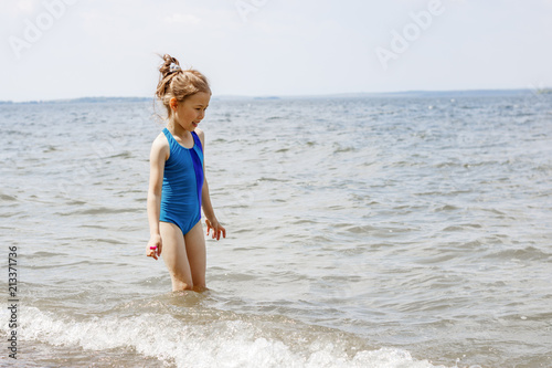 A girl in a blue swimsuit saw the sea for the first time