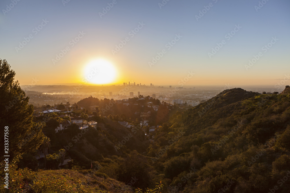 Smoggy orange sunrise view from Runyon Canyon Park towards Hollywood and Downtown Los Angeles, California.