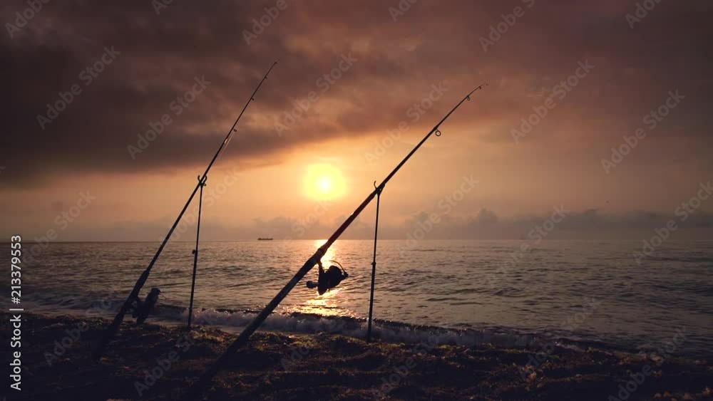 Beautiful sunrise over the sea, sunrise. Fishing rod on the beach and sailing cargo ships. Beautiful sunrise over the sea, sunrise. Fishing rod on the beach and sailing cargo ships.