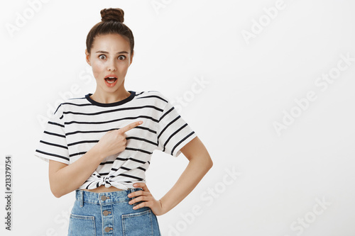 Have you seen more incredible copy space. Portrait of amazed and surprised good-looking female, dropping jaw from excitement, pointing at upper right corner, directing at interesting person