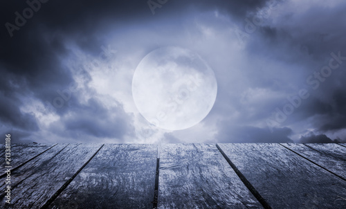 Halloween background. Spooky sky with full moon and wooden table