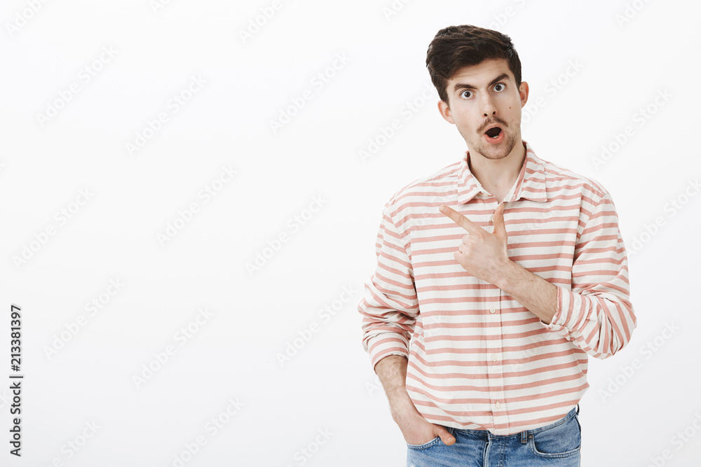 Guy fighting with girlfriend asking to explain rumors about her. Shot of displeased intense and concerned caucasian man with beard, talking and pointing at upper left corner, standing over gray wall Guy fighting with girlfriend asking to explain rumors about her. Shot of displeased intense and concerned caucasian man with beard, talking and pointing at upper left corner, standing over gray wall