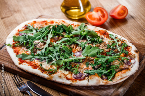 Pizza with chicken, arugula, cheese and onions on wooden rustic table. Top view.