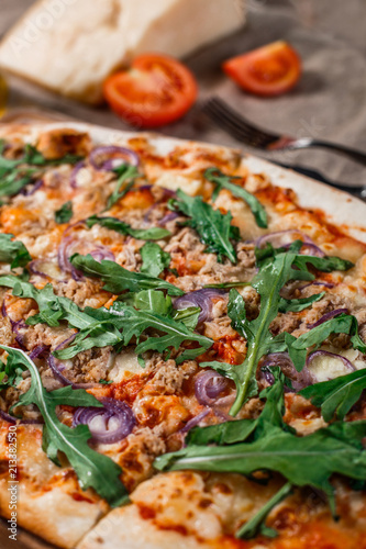 Pizza with chicken, arugula, cheese and onions on wooden rustic table. Top view.