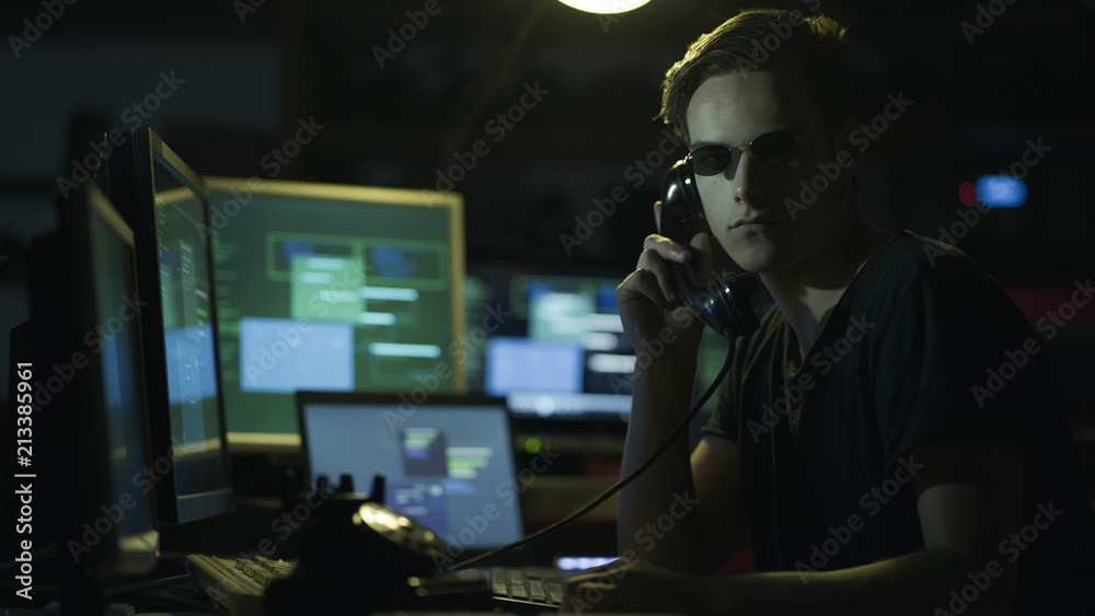 Hacker hoding a receiver and computer screens