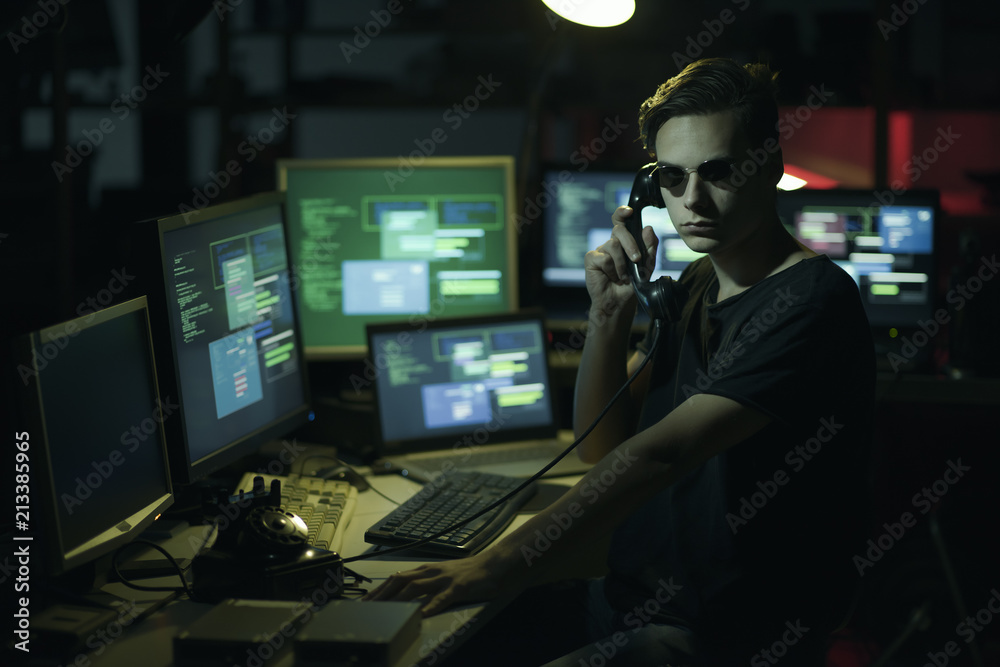 Hacker hoding a receiver and computer screens Hacker hoding a receiver and computer screens