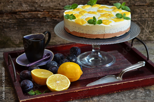 Cold cheesecake with chia. Sliced lemons on a wooden tray. Cup of coffee