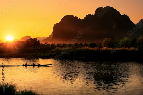 Εκτύπωση καμβά Sunset over Nam Song River with silhouetted rock formations and a boat in Vang V