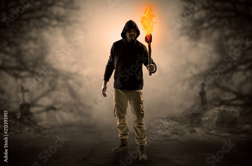 Man with burning flambeau coming from thicket and looking something  © ra2 studio