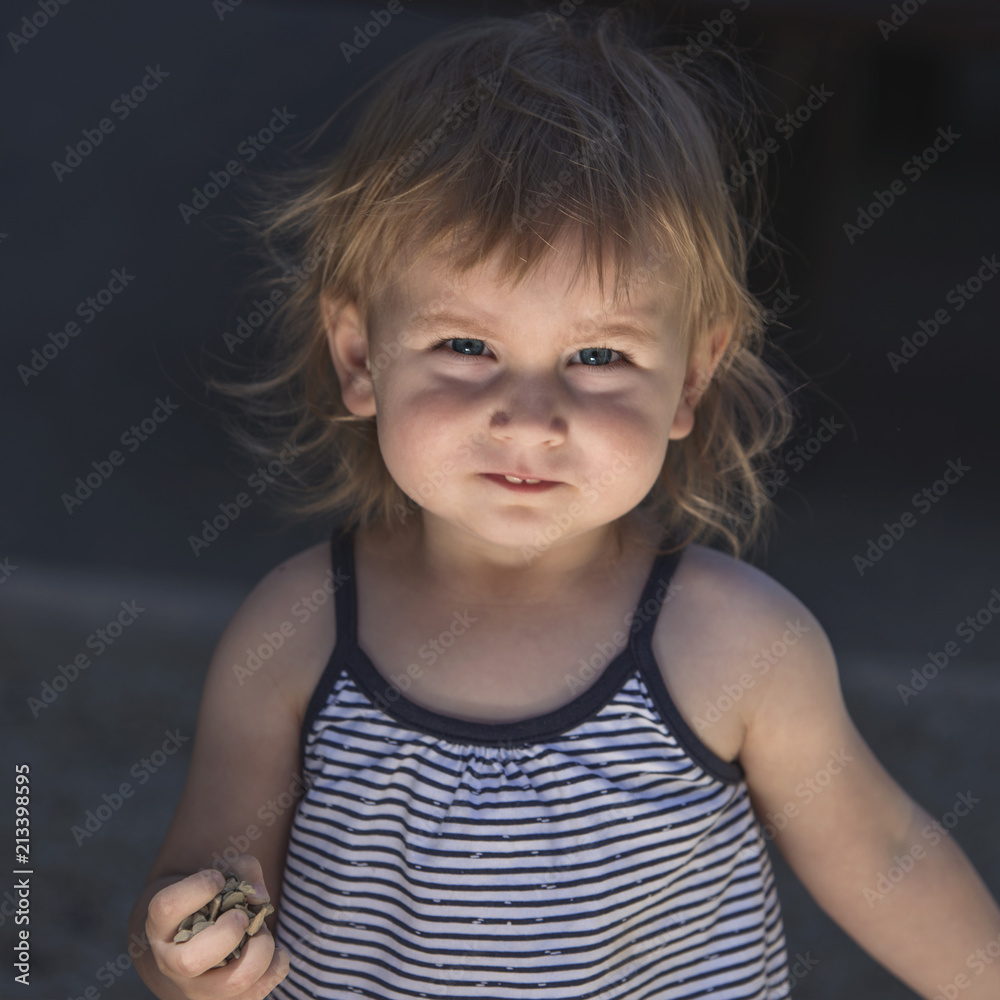 fair-haired little girl with blue eyes and a resolute expression clutching a handful of stones in her fist, fair-haired little girl with blue eyes and a resolute expression clutching a handful of stones in her fist,