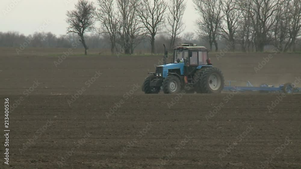 Tractor cultivating land in extreme close up Tractor disc ground. Rural locality. The land is ready for planting grass. Tractor handles field. Disking. The land is ready for planting Tractor cultivating land in extreme close up Tractor disc ground. Rural locality. The land is ready for planting grass. Tractor handles field. Disking. The land is ready for planting
