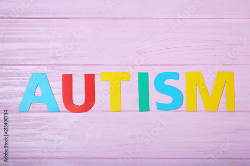 Word AUTISM on color background, top view