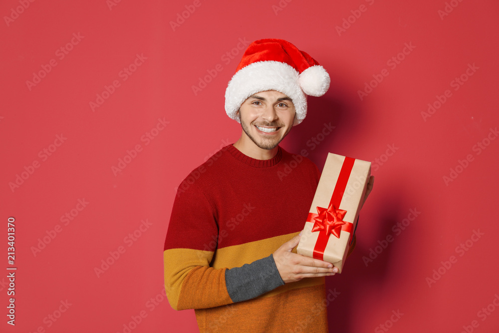 Young man with Christmas gift on color background Young man with Christmas gift on color background