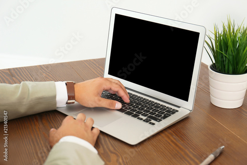 Man in office wear using laptop at table indoors
